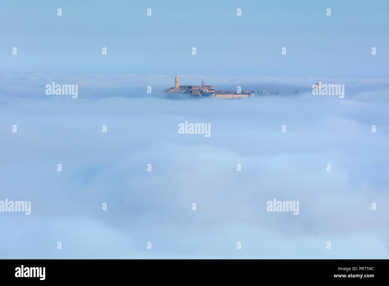 Pienza la Torre dell Orologio e Duomo Torre Campanaria salire sopra le nuvole e la nebbia che copre la Val d'Orcia al di sotto, UNESCO, Toscana, Italia Foto Stock