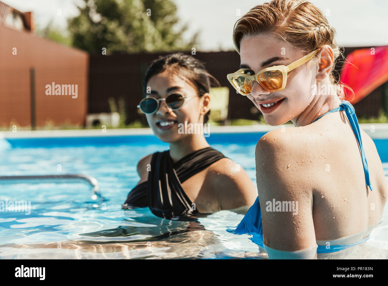Felice ragazze multietnica in occhiali da sole rilassante in piscina Foto  stock - Alamy
