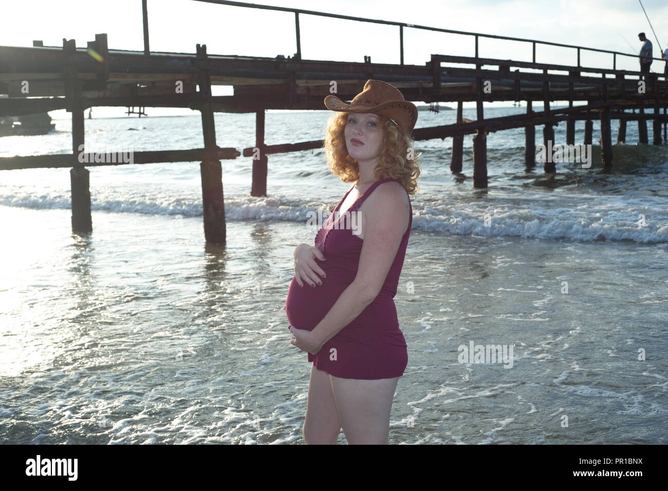 Gravidanza donna giocare sulla riva del mare costiero Foto Stock