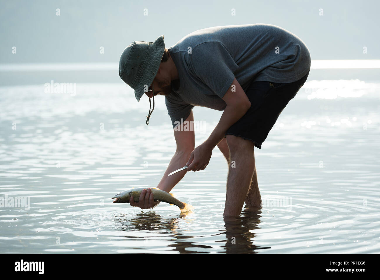 Fisherman tenendo un pesce nelle vicinanze Riverside Foto Stock