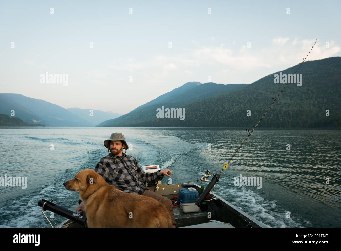 Fisherman pesca con il suo cane nel fiume Foto Stock