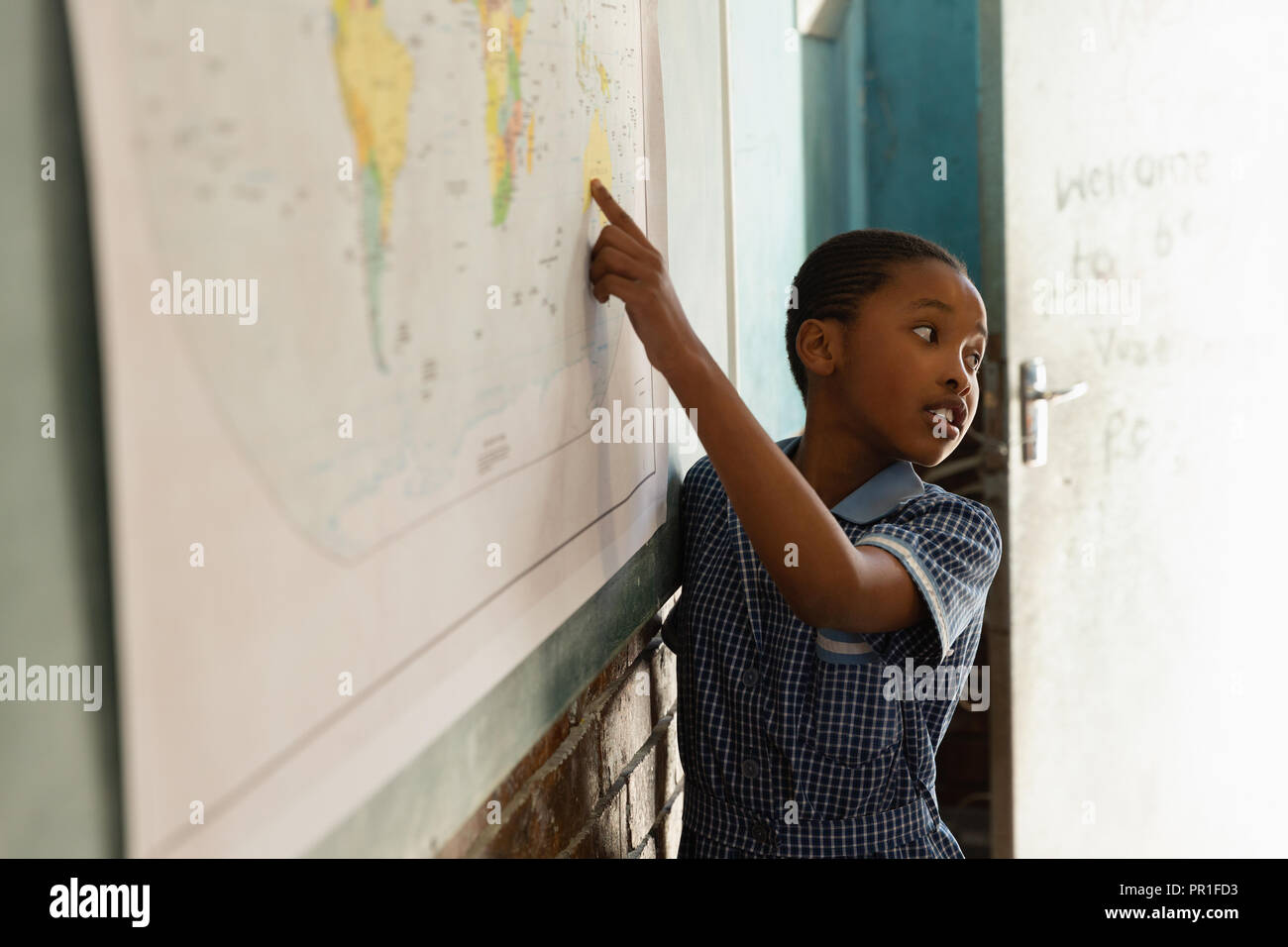 Scolaro spiegando sulla mappa del mondo in classe Foto Stock