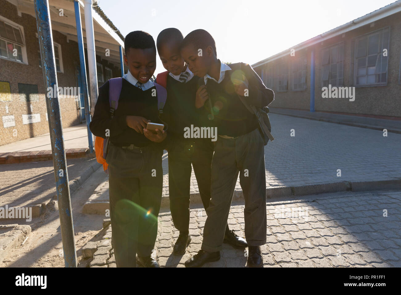 Schoolkids tramite telefono cellulare nel campus della scuola Foto Stock