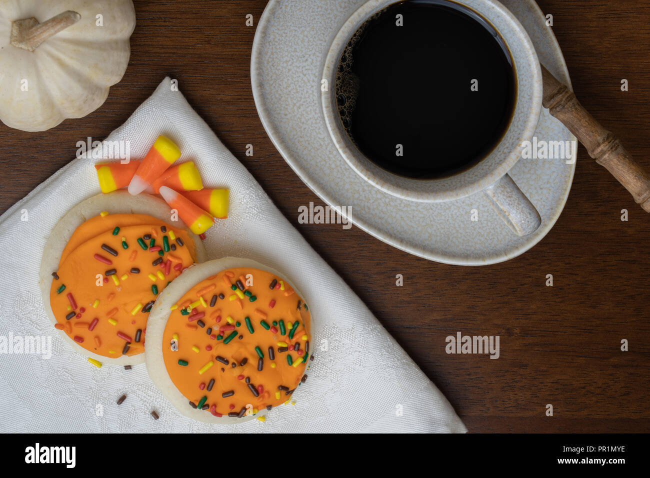 Nero caffè in tazza con piattino e cucchiaio rustico con biscotti, caramelle, mais e un mini bianco piatto di zucca lay Foto Stock
