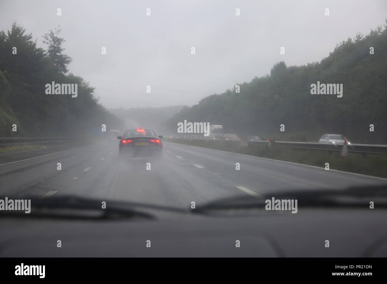 Il traffico in Heavy Rain per M3 Inghilterra del sud vista attraverso il parabrezza Foto Stock