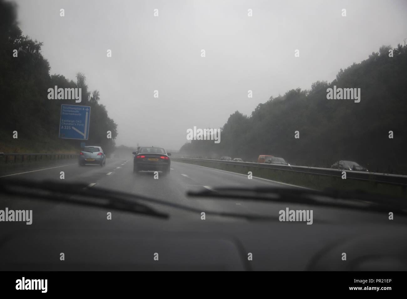 Il traffico in Heavy Rain per M3 Inghilterra del sud vista attraverso il parabrezza Foto Stock