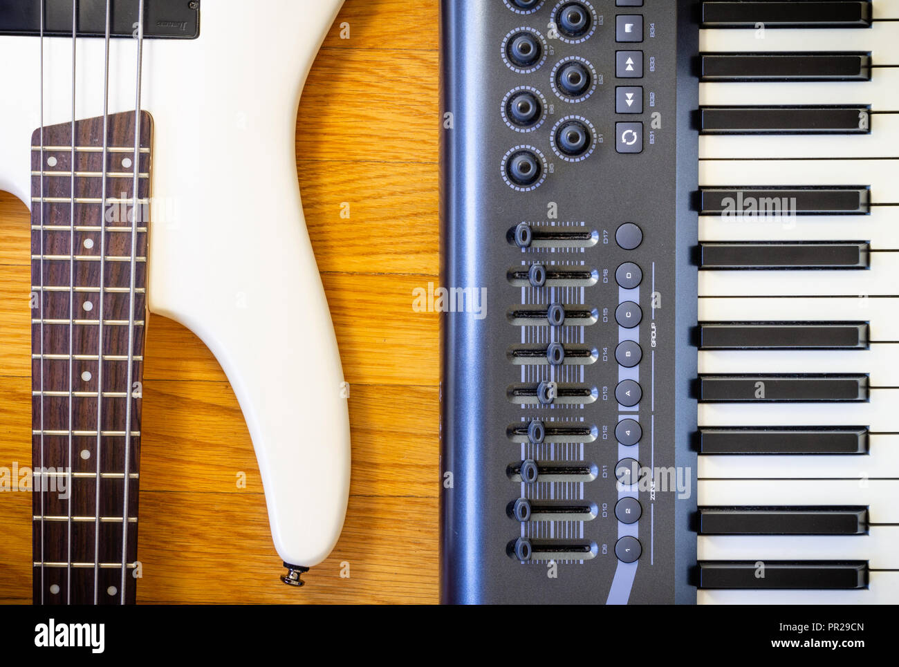 Un sfondo di legno con un set di strumenti musicali costituiti da una tastiera e una chitarra basso. Foto Stock
