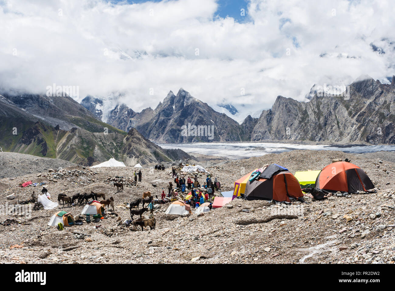Il trekking e facchini in Goro II campeggio prima Masherbrum (K1) coperto di nuvole, ghiacciaio del Baltoro, Karakoram, Pakistan Foto Stock