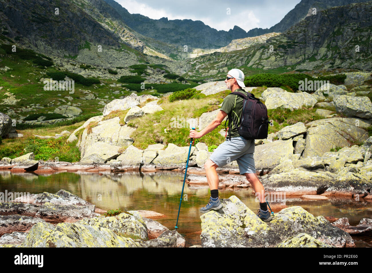 Escursionista con zaino in piedi sulle rocce in montagna Foto Stock