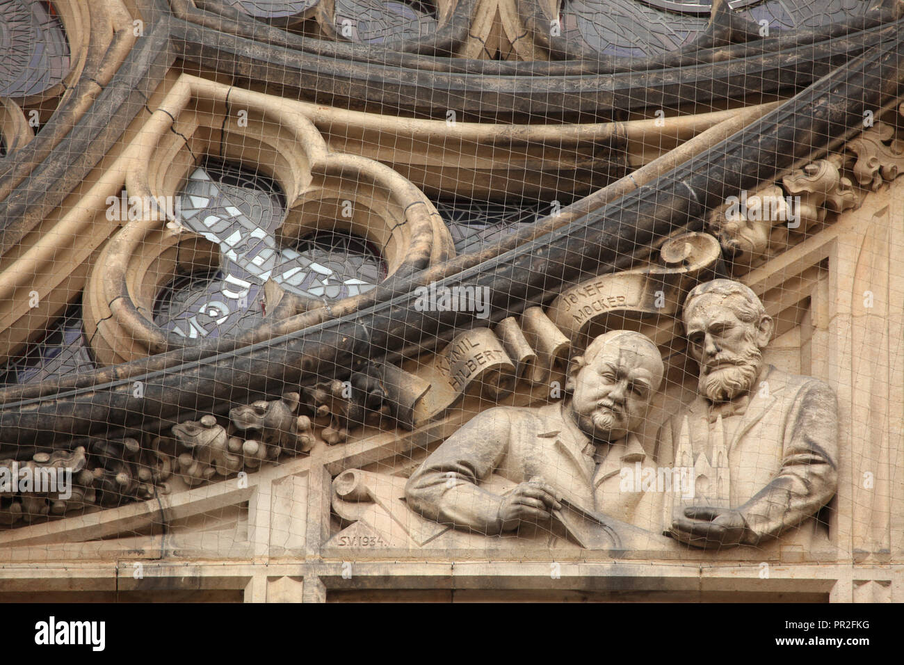 Ritratti di architetti ceca Kamil Hilbert (L) e Josef beffardo (R) raffigurato in bassorilievo da scultore ceco Vojtěch Sucharda (1934) posto sotto il rosone sulla facciata principale di San Vito' cattedrale nel Castello di Praga a Praga, Repubblica Ceca. Foto Stock