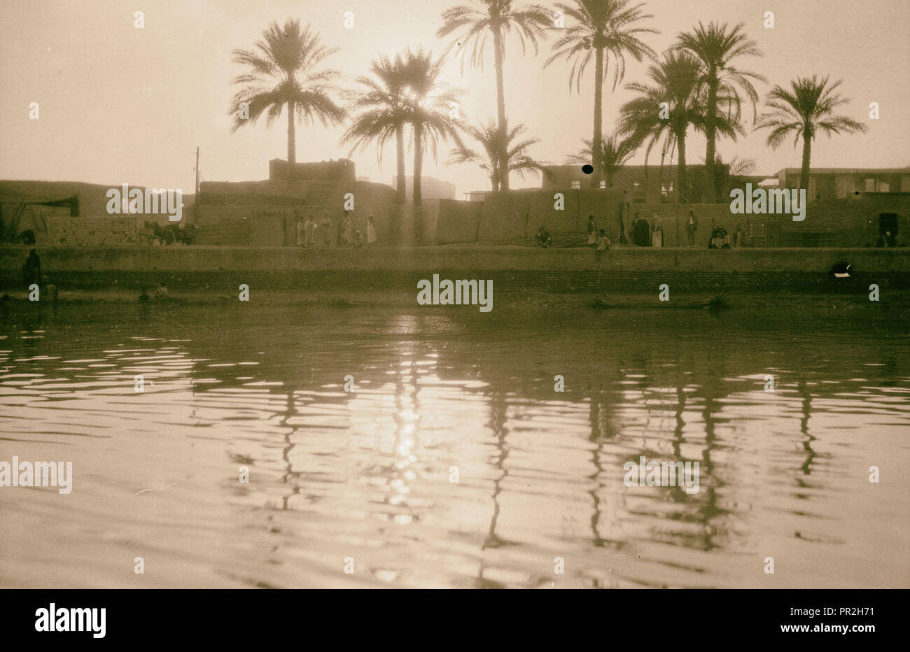 L'Iraq, sul fiume di persone a barche con città sull'altro lato. 1932, l'Iraq Foto Stock
