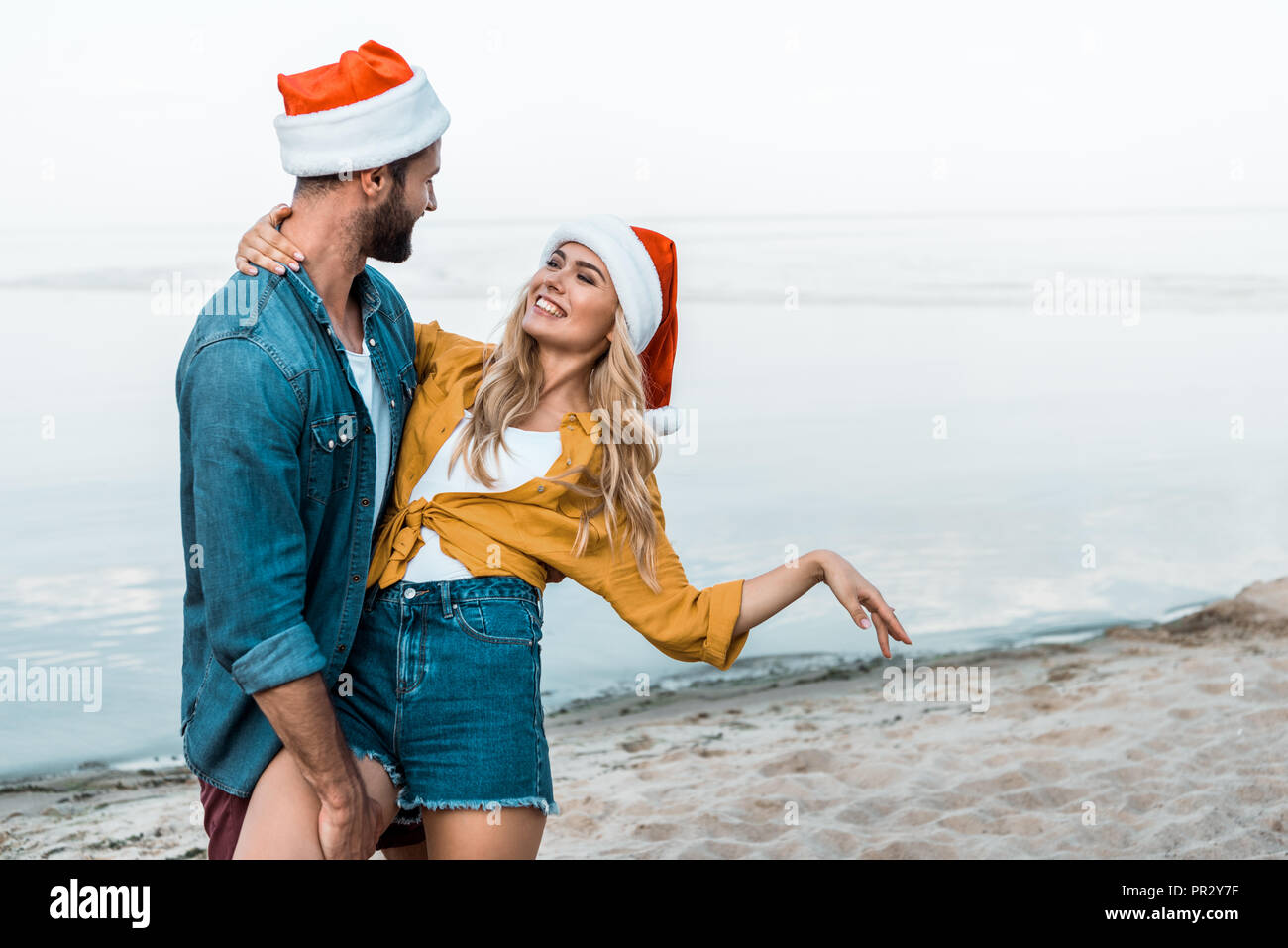 Matura in cappelli di Babbo Natale e abbraccia il divertimento sulla spiaggia Foto Stock