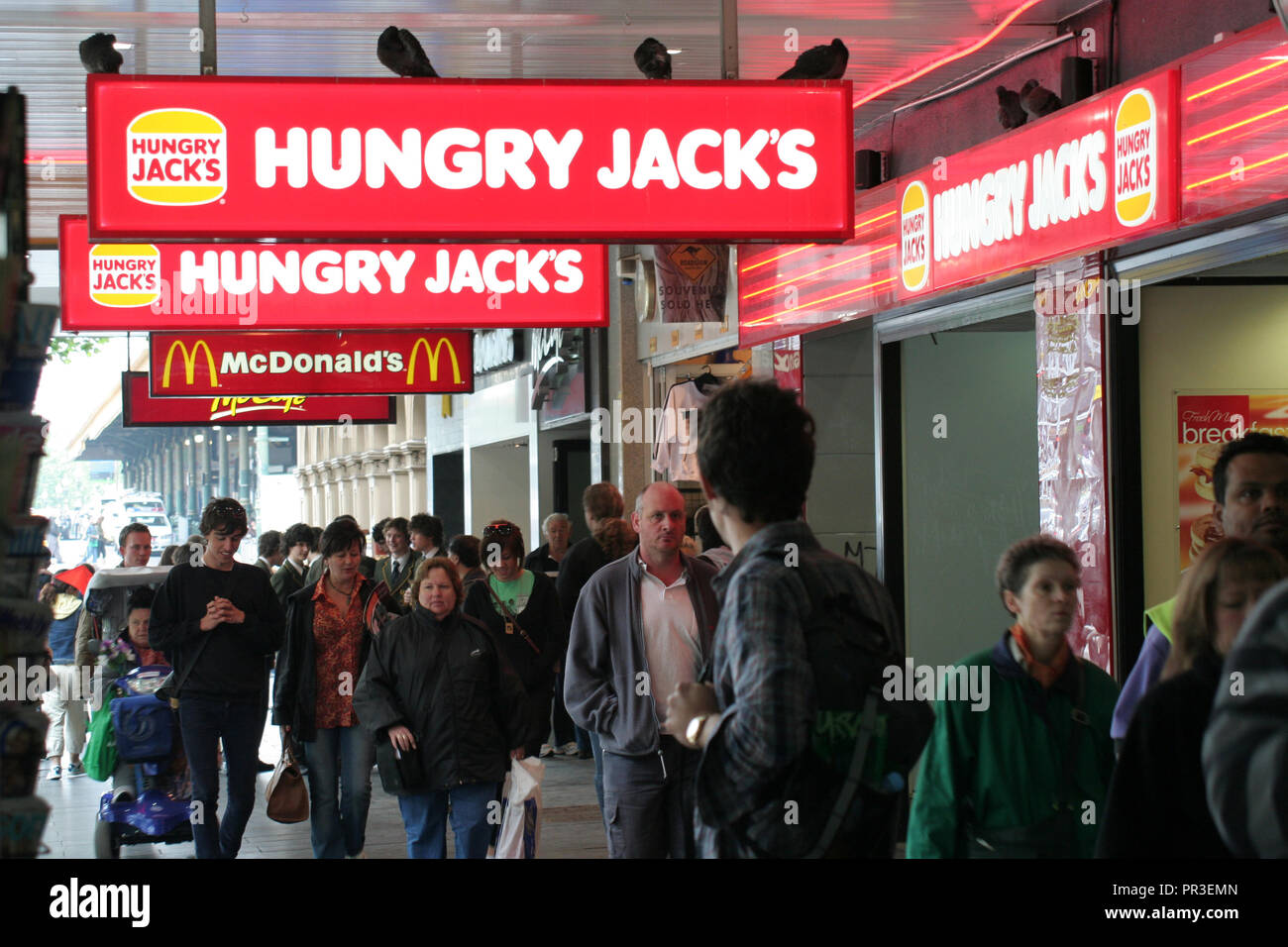 La folla a piedi sotto Hungry Jacks e MCDONALD'S segni in Swanston Street, Melbourne, Victoria, Australia Foto Stock