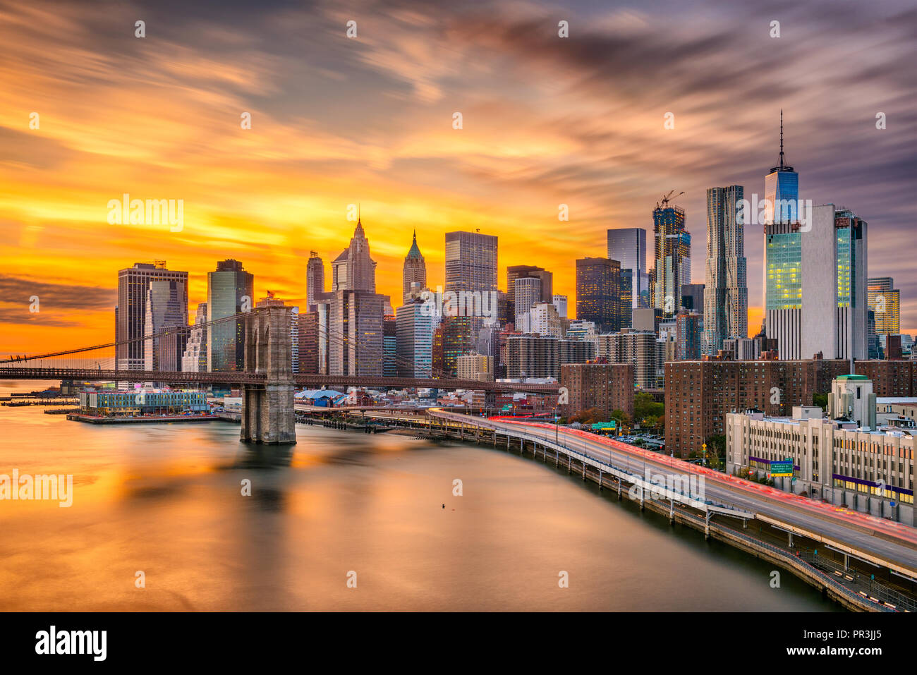 New York, New York, Stati Uniti d'America inferiore dello skyline di Manhattan su East River con il ponte di Brooklyn dopo il tramonto. Foto Stock
