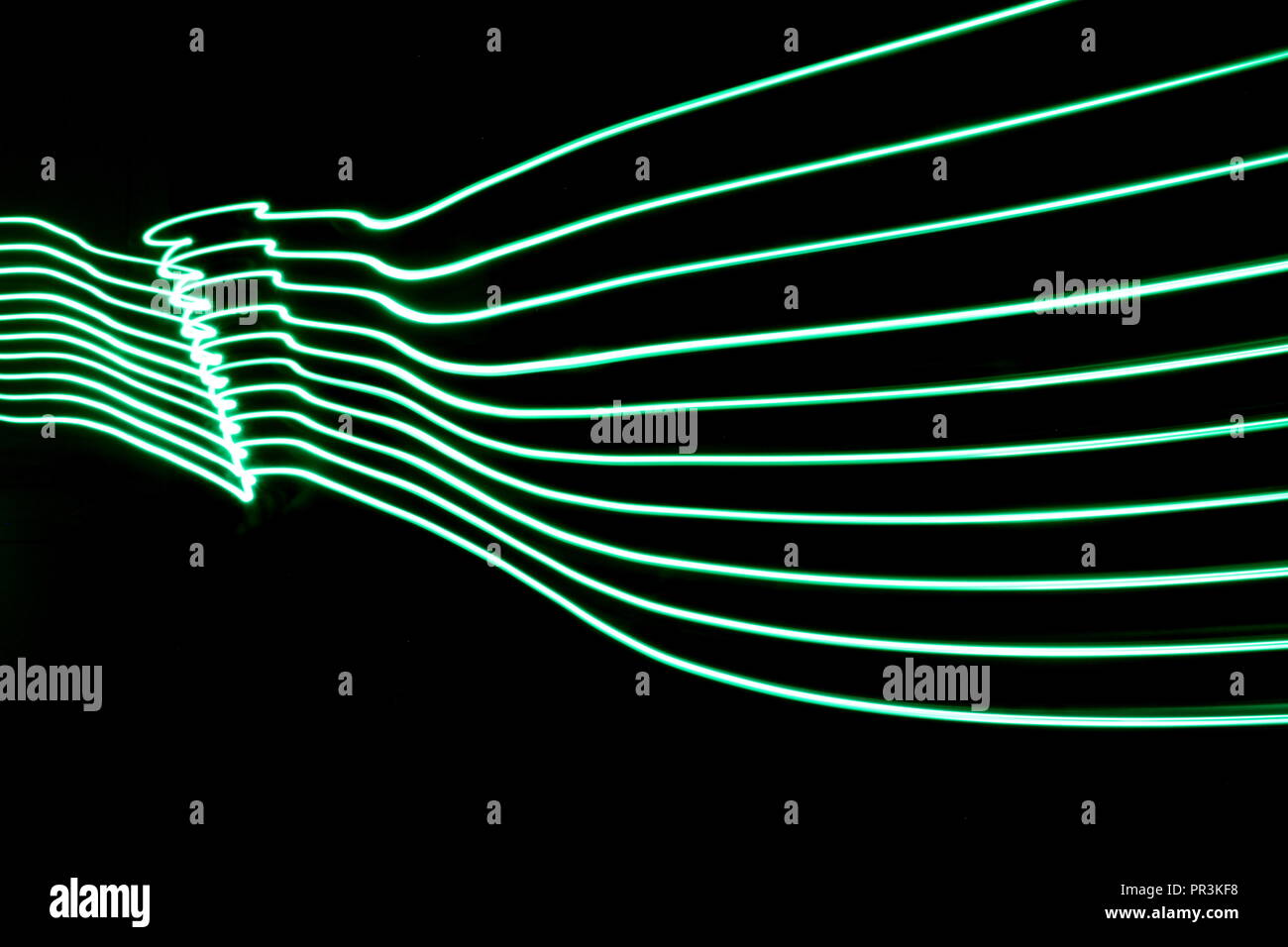 Una lunga esposizione di luce fotografia pittura, linee parallele di verde vivace scomparendo in lontananza contro uno sfondo nero Foto Stock