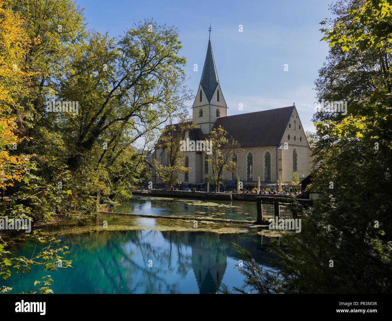 Il pozzo "Blautopf' a Blaubeuren, in Germania con una chiesa in backgrund Foto Stock