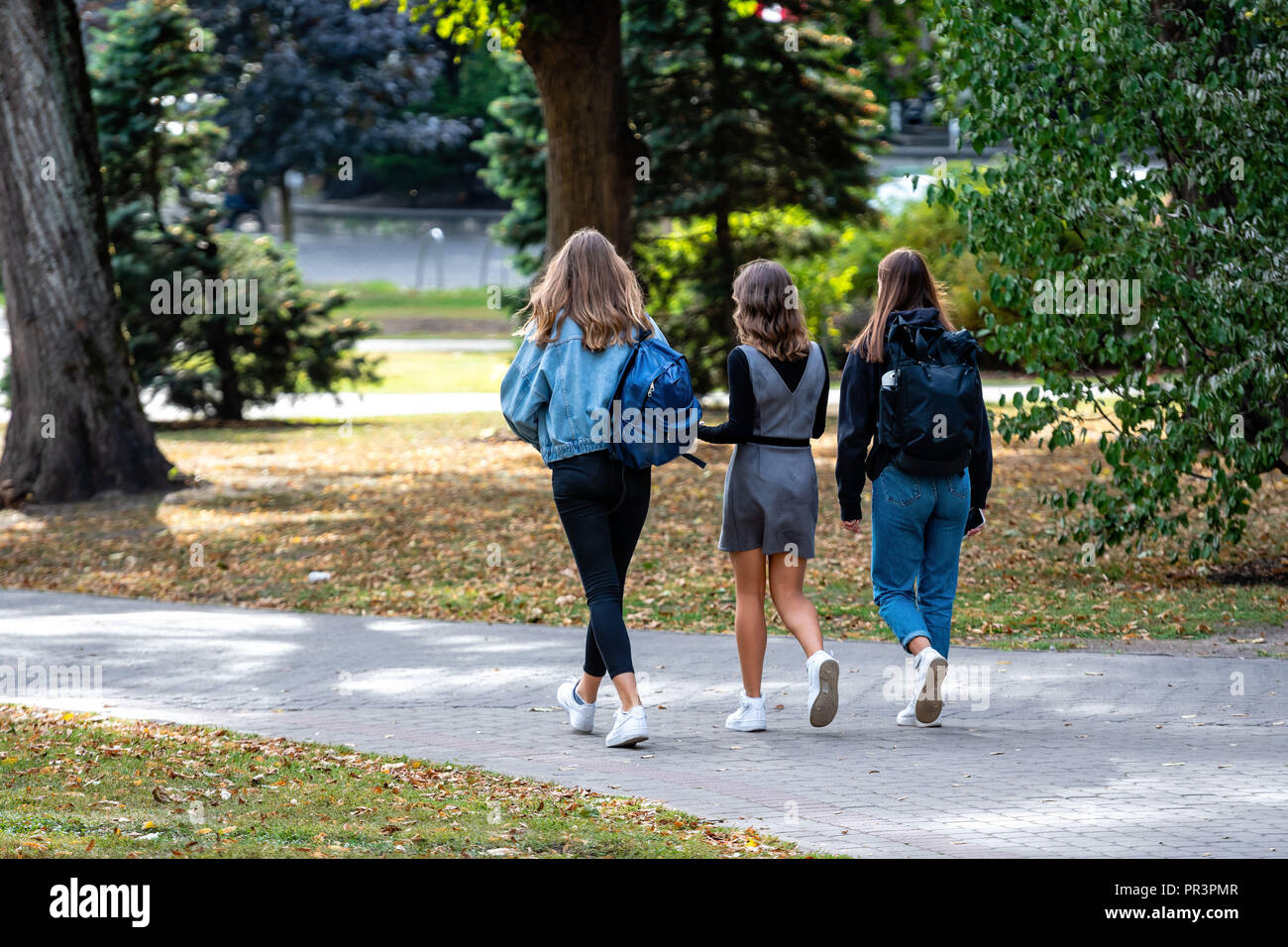 Tre ragazze con uno zaino camminando lungo il parco della città. Foto Stock