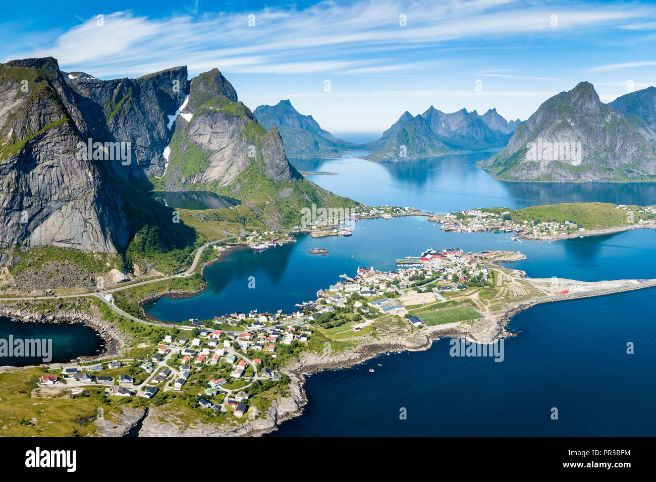 Reine Lofoten in Norvegia, vista aerea del Norvegese tradizionale villaggio di pescatori di cui sopra circolo polare con il blu del mare e delle montagne durante la soleggiata estate artica, Foto Stock