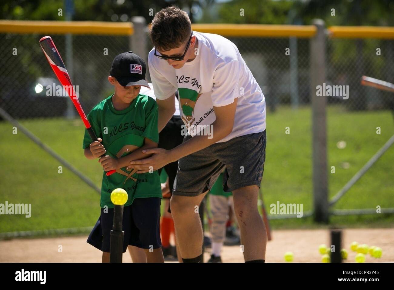 CAMP FOSTER, Okinawa, Giappone - Lancia Cpl. Lucas Smith regola un bambino posizione di battuta in corrispondenza di una gioventù clinica di baseball luglio 29 a bordo Camp Foster, Okinawa, in Giappone. Il baseball clinic ha ospitato quattro diverse stazioni: colpendo, acceso, cattura e gettando, e un infield grounders fly stazione. Una volta completate le varie stazioni, hanno gareggiato per vedere chi avrebbe vinto per le tre stazioni: esecuzione di colpire e di buttare un bersaglio. Smith è con il combattimento reggimento logistica 35, terzo Marine Logistics Group, III Marine Expeditionary Force. ( Foto Stock