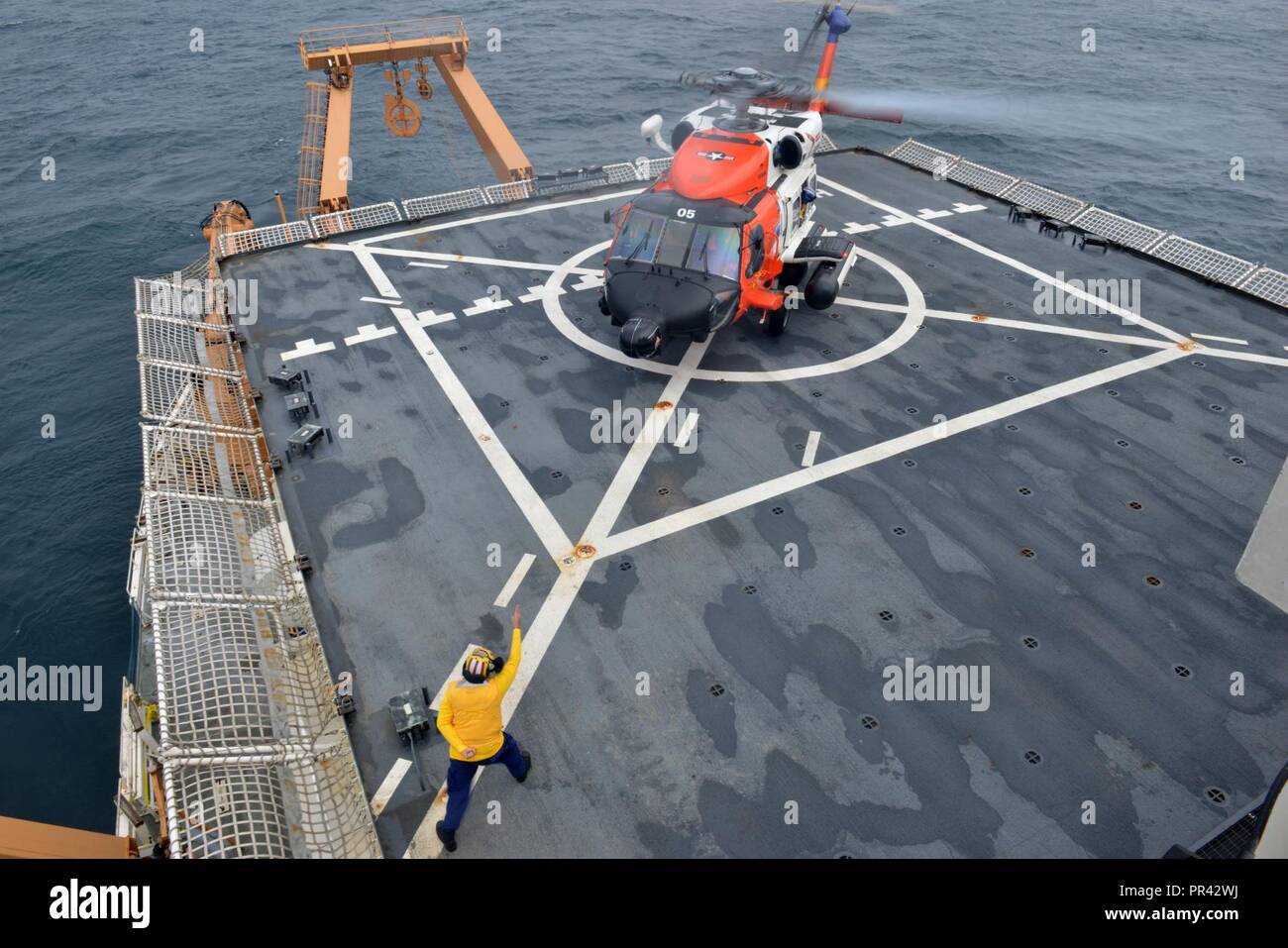 Coast Guard Petty Officer 1. Classe Sean Carrillo segnala una stazione aria Kodiak MH-60 Jayhawk elicotteri aerei equipaggio durante un "touch and go" di atterraggio e di decollo di formazione sul funzionamento del guardacoste Healy del ponte di volo come la taglierina transita il Chukchi mare al largo della costa di Alaska, 28 luglio 2017. La guardia costiera del ruolo di leadership nel fornire una continua presenza artico è essenziale per la sicurezza nazionale, dominio marittimo consapevolezza, la libertà di navigazione, U.S. interessi sovrani e della ricerca scientifica. Stati Uniti Coast Guard Foto Stock