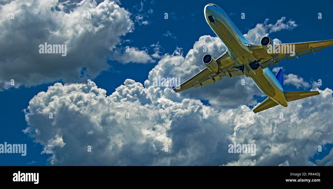 Un'azione skyscape vista di un passeggero commerciale jet aeromobili battenti closeup nella vibrante blu cielo, con sviluppato colorate di bianco cumulonimbus cloud. Foto Stock