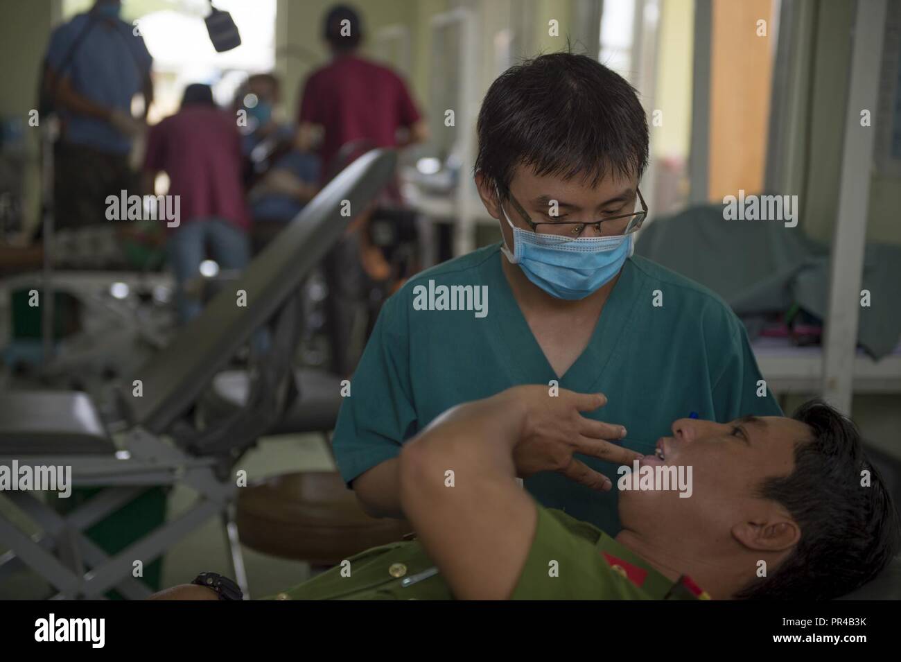 Il Thanh Dinh Nhan, un dentista con l'Oriente incontra l'Occidente, parla con la polizia Capt. Vu fare Thanh Hai prima di un esame dentale in una fase preliminare di servizio sanitario in caso di outreach durante l angelo del Pacifico (PAC ANGEL) 18-2 in Nui Thanh, Quang Nam provincia, Vietnam, Sett. 9, 2018. PAC Angel è un multilaterale di assistenza umanitaria civile e militare, di impegno che migliora di strutture militari di partenariati nell'Indo-Pacifico fornendo anche la salute medica outreach, civico progetti di ingegneria e di esperto in materia di scambi tra le forze dei partner. Foto Stock