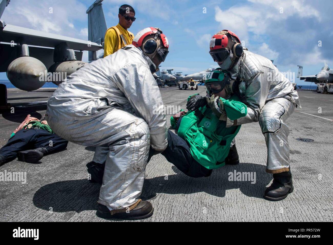 Mare delle Filippine (17 settembre 2018) marinai del crash e equipaggio di soccorso rimuovere la simulazione di una vittima come parte di una massa casualty drill sul ponte di volo della Marina è distribuita portaerei USS Ronald Reagan (CVN 76) durante la Valiant scudo 2018. La biennale, SOLO NEGLI STATI UNITI, campo-esercizio di formazione si concentra sull'integrazione di formazione congiunta tra Stati Uniti Navy, Air Force e Marine Corps. Questo è il settimo esercizio nel Valiant scudo serie che ha avuto inizio nel 2006. Foto Stock