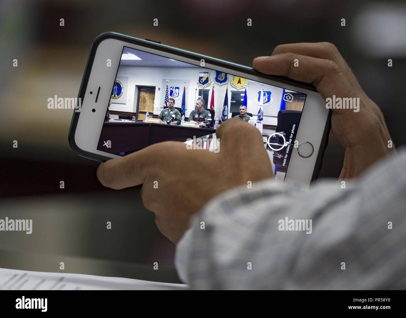 Un reporter dal Pacifico News Center prende una foto della Valiant scudo esercizio congiunto gruppo di controllo il direttore e lo staff nel corso di una conferenza stampa presso Andersen Air Force Base, Guam sett. 17, 2018. Valiant Shield è un solo negli Stati Uniti, biennale la formazione sul campo di allenamento (FTX) con un focus sulla integrazione di formazione congiunta in un Blu-acqua ambiente tra le forze americane. Questa formazione consente un vero-mondo proficiency nel sostenere forze congiunte attraverso il rilevamento, la localizzazione, tracking e unità di impegno in mare e in aria, sulla terra e nel cyberspazio in risposta ad una gamma di aree di missione. Foto Stock