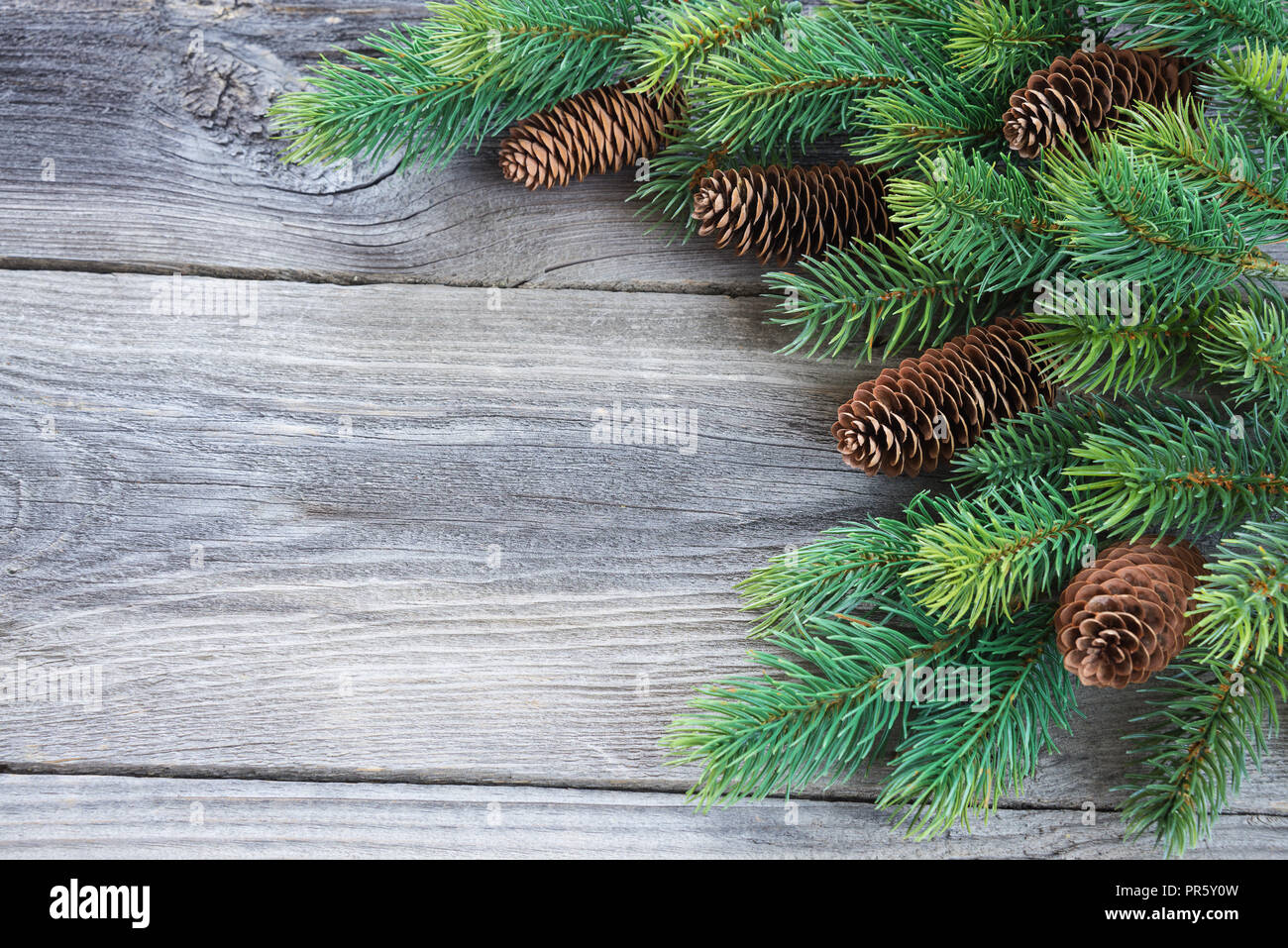 Natale vintag telaio composto di pigne e rami di abete rosso sullo sfondo della vecchia non verniciata di tavole di legno; con copy-spazio Foto Stock