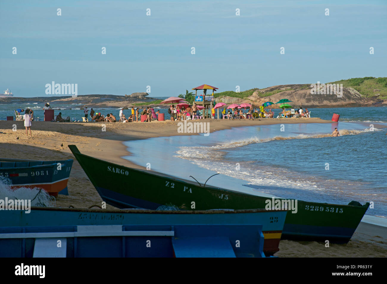 Canoe di pescatori e bagnanti sole in spiaggia urbana, Praia da Costa, Vila Velha, Espirito Santo, Brasile Foto Stock