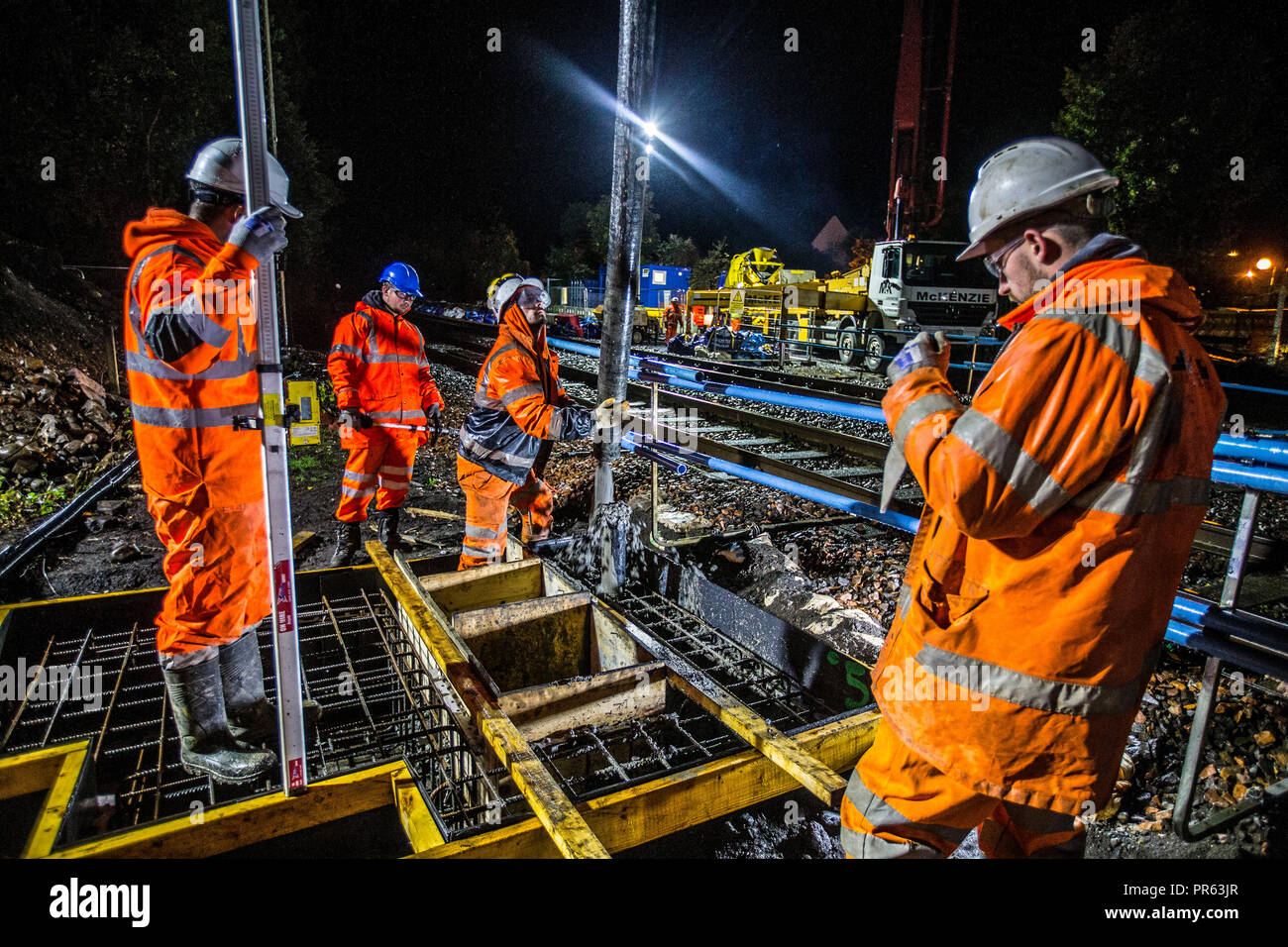 La costruzione della ferrovia lavoratori colata di cemento di notte Foto Stock