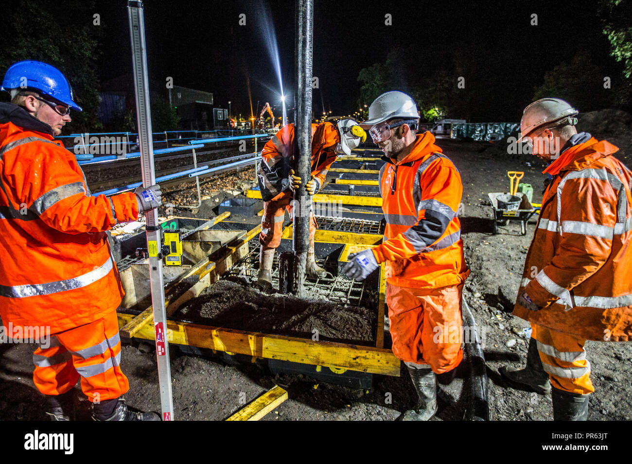 La costruzione della ferrovia lavoratori colata di cemento di notte Foto Stock
