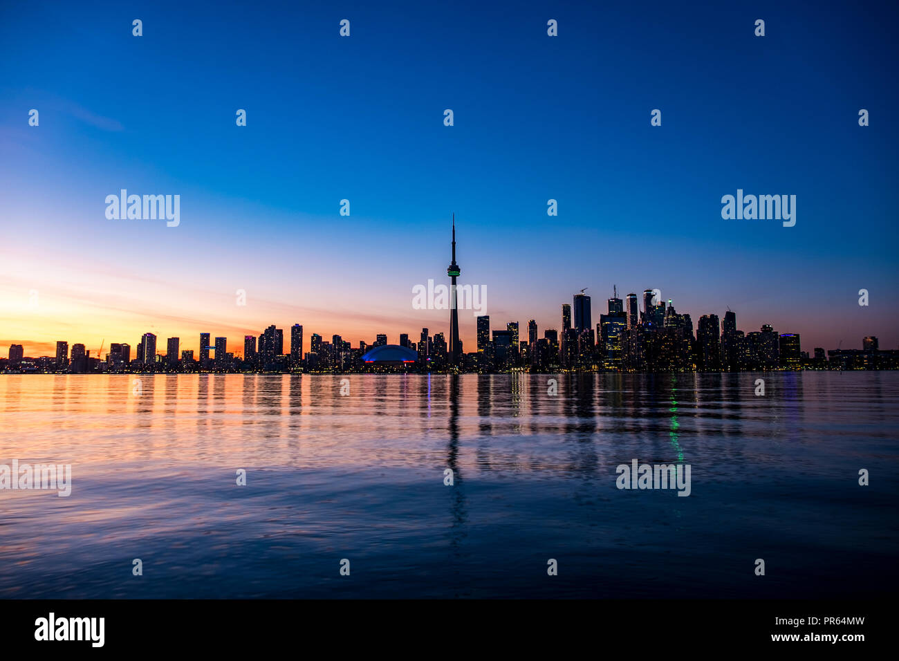 Lo skyline del centro cittadino di Toronto dal centro isola guardando attraverso il lago Ontario come il sole tramonta Foto Stock