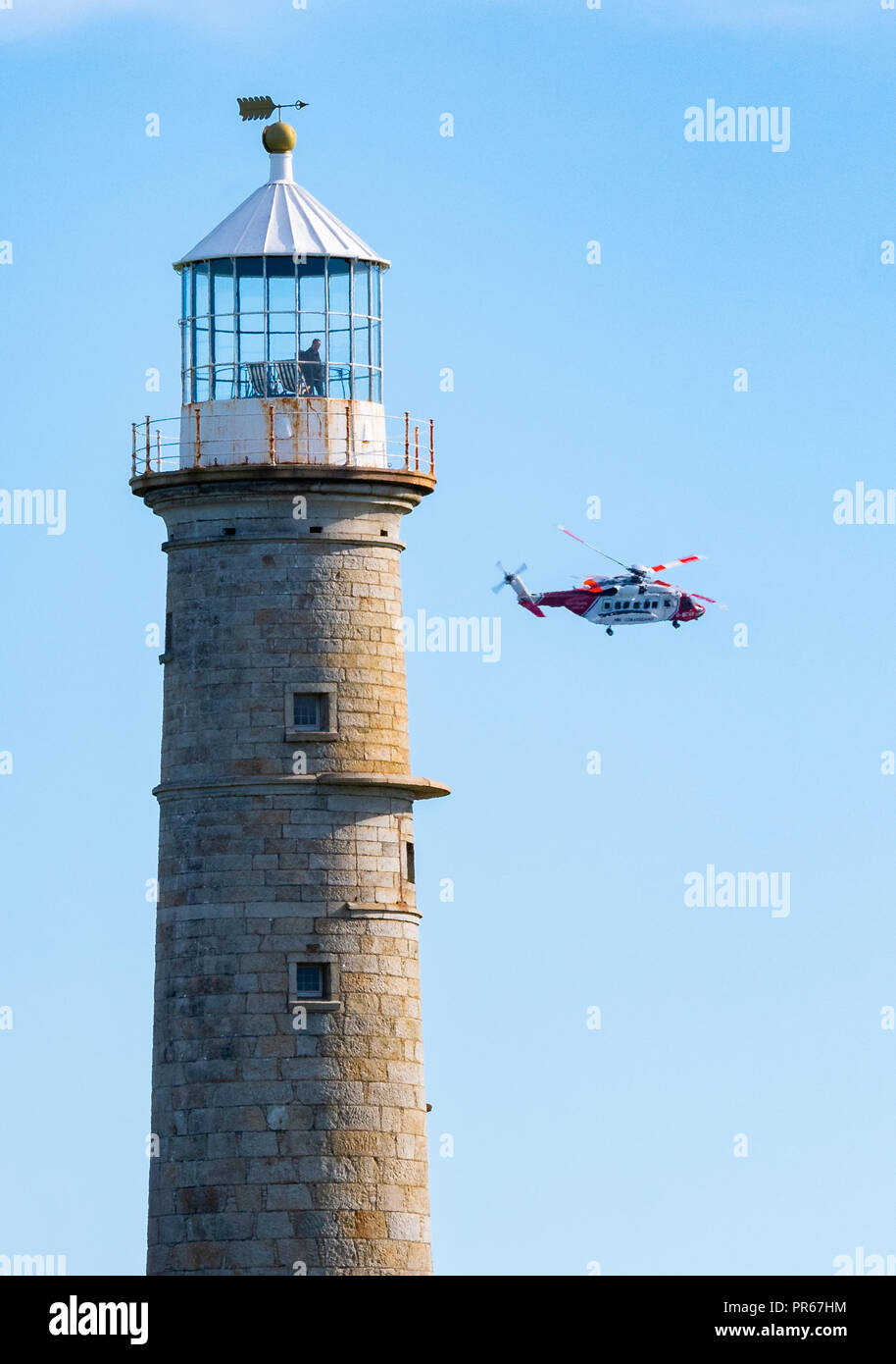 HM Coastguard elicottero volando vicino al vecchio faro di luce durante una operazione di salvataggio sull isola di Lundy fuori della costa del Devon Regno Unito Foto Stock