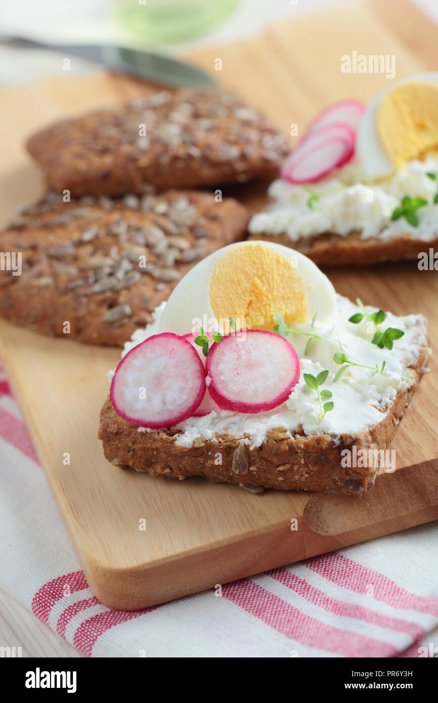 Panini con pane di segale, crema di formaggio, uova sode, ravanello e timo Foto Stock