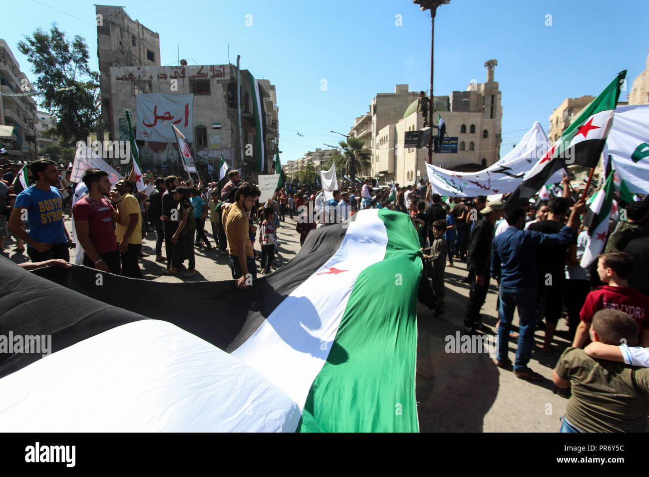 La gente si vede tenendo un enorme bandiera lunga durante una manifestazione di protesta nella città di Eriha in Idlib per chiedere la liberazione di sei persone detenute dal regime siriano. Foto Stock