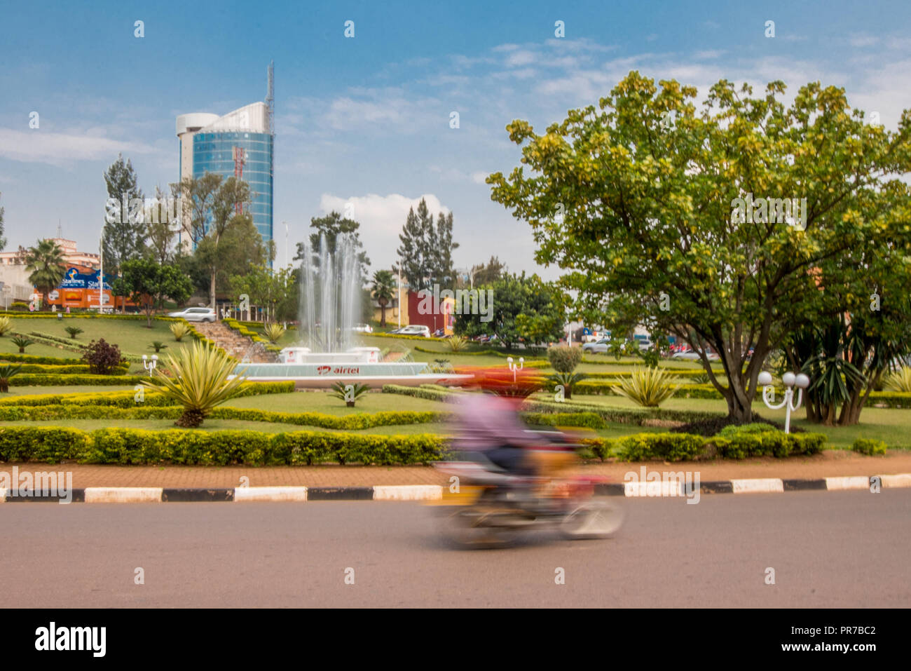 A Kigali, Ruanda - Settembre 20, 2018: un 'moto" (moto) a una rotonda vicino al centro della città, con Kigali City Tower in background Foto Stock