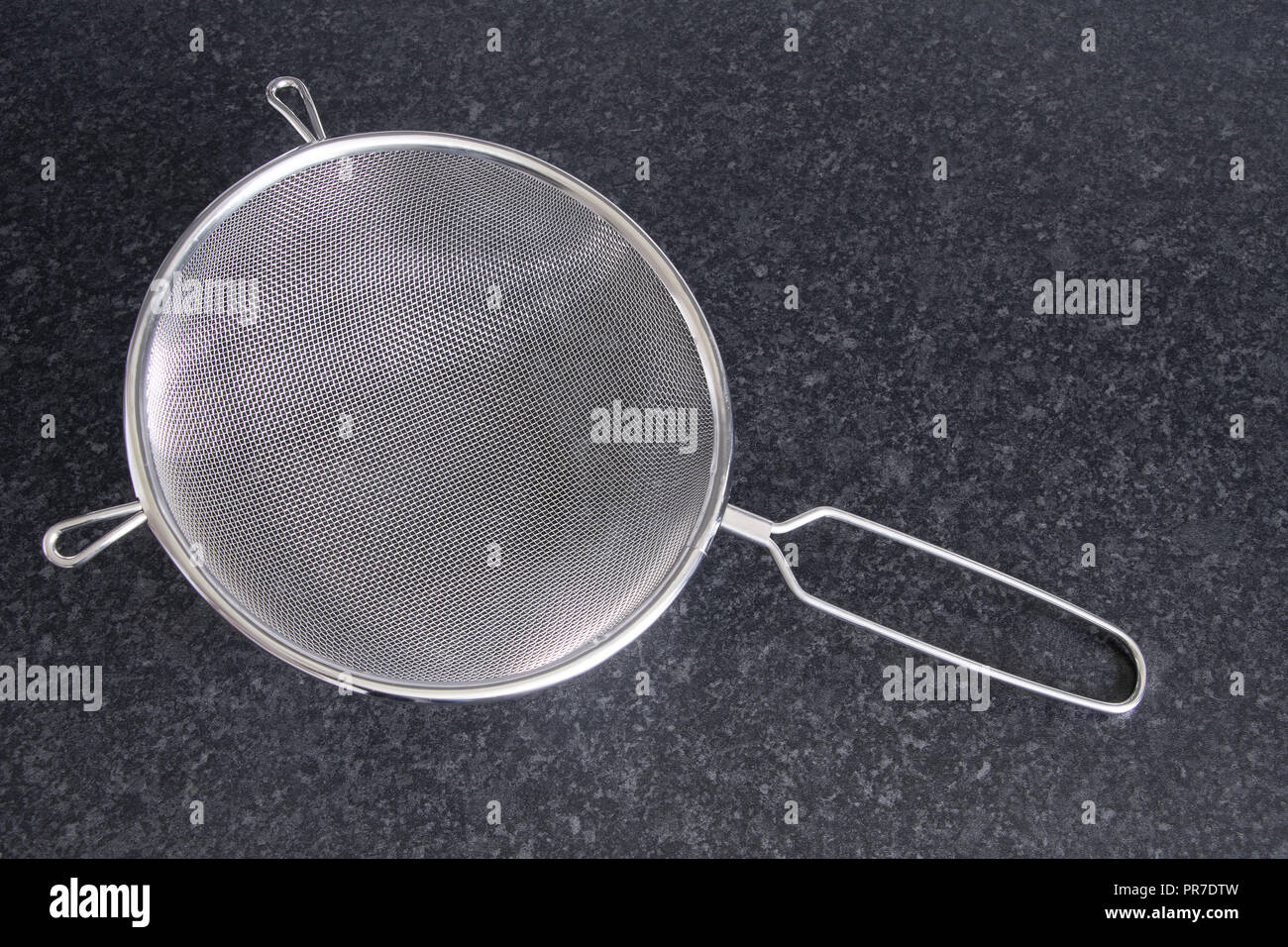 Setaccio da cucina su un colore scuro sul bancone Foto Stock