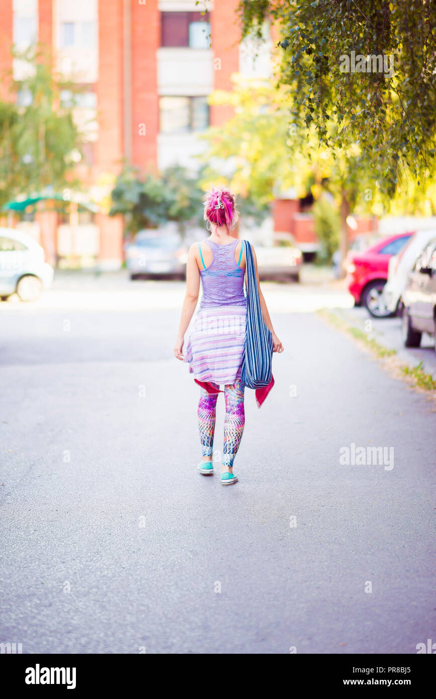 Giovane donna in abiti colorati di camminare sulla strada Foto Stock