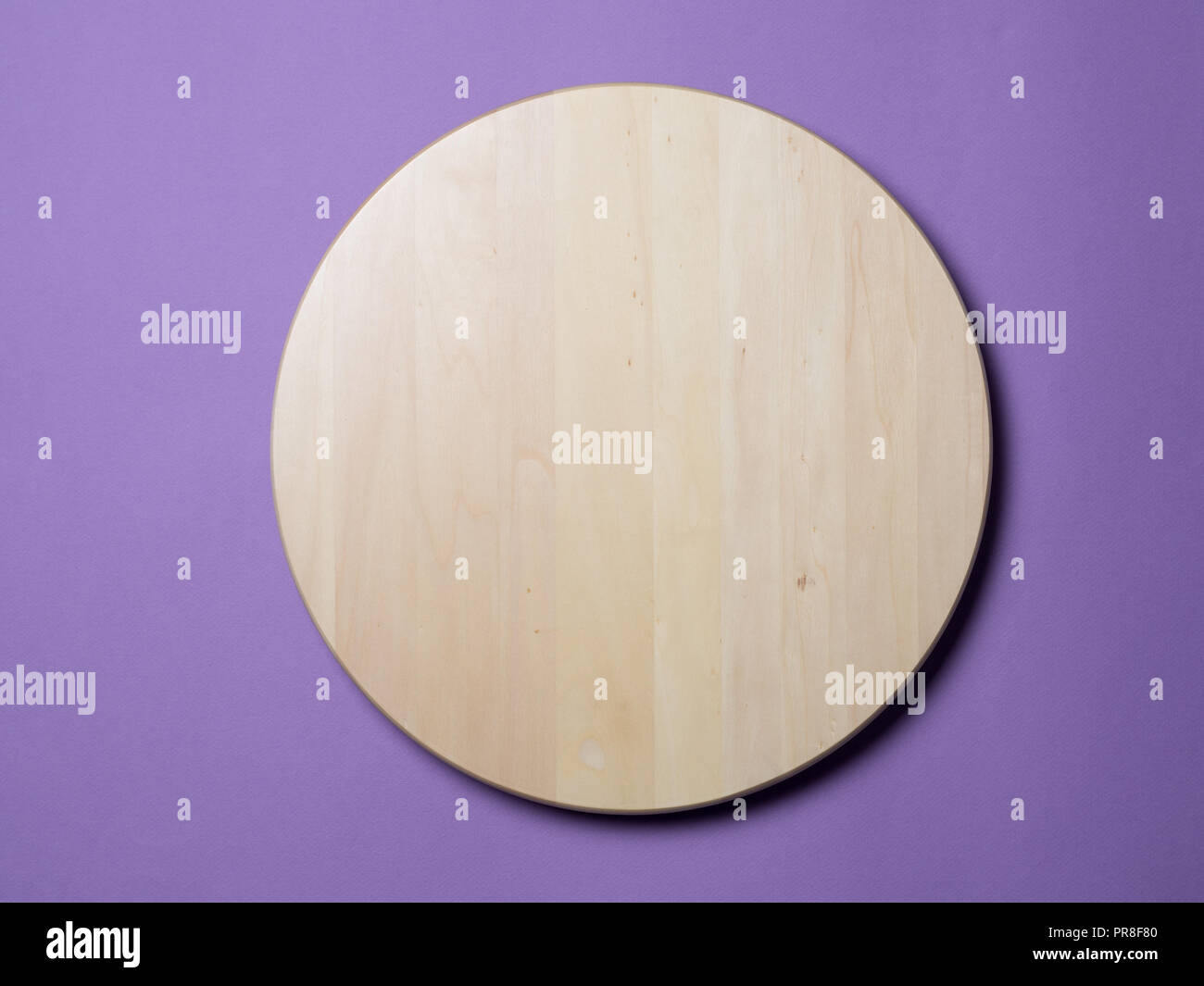 Vuoto in legno vassoio rotondo o solcatore, tagliere su sfondo lilla. Hard Light. Vista superiore piatta o laici. Foto Stock