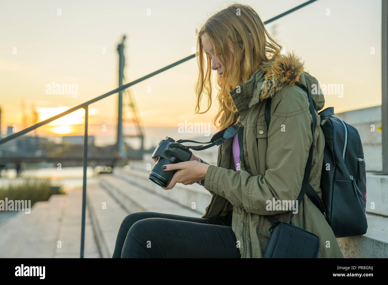 Giovane donna con una reflex è controllare le anteprime delle immagini sul display della fotocamera Foto Stock