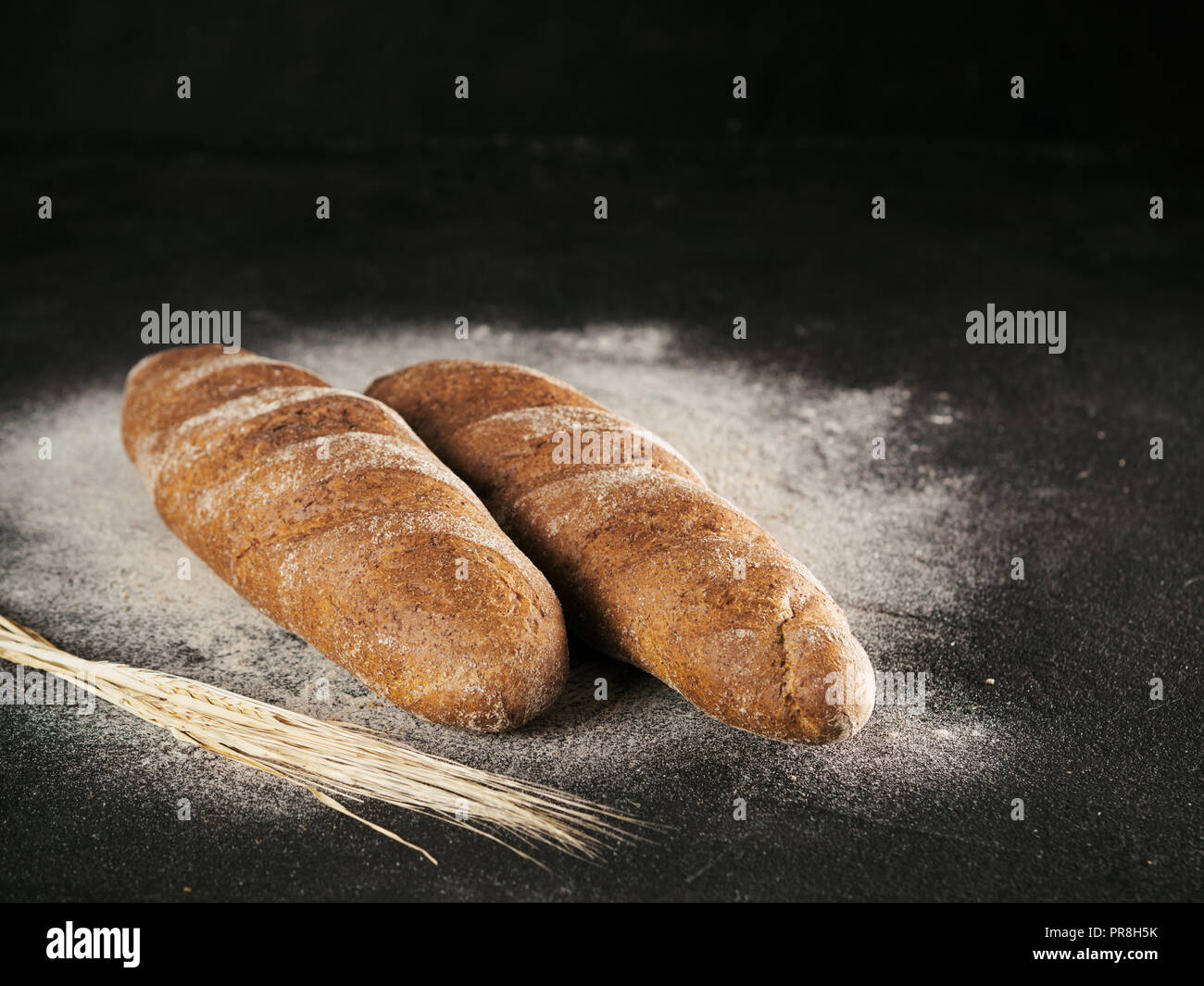 Due interi in casa pane di segale pane di farina di grano saraceno su nero testurizzato sfondo. Copia dello spazio. Tasto basso Foto Stock
