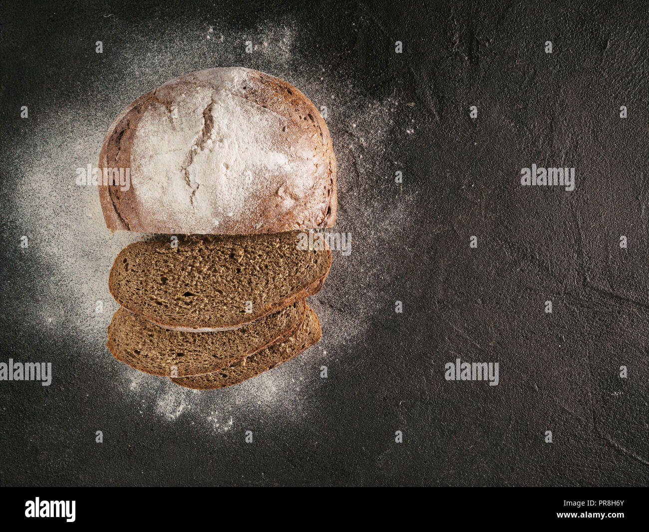 Fette di pasta madre casalinga pane di segale con la farina di segale sul nero testurizzato sfondo. Vista superiore o flat-lay. Copia dello spazio. Tasto basso Foto Stock