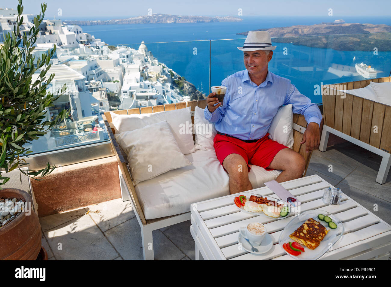 Uomo in un bar in riva al mare ha la colazione e beve caffè Foto Stock