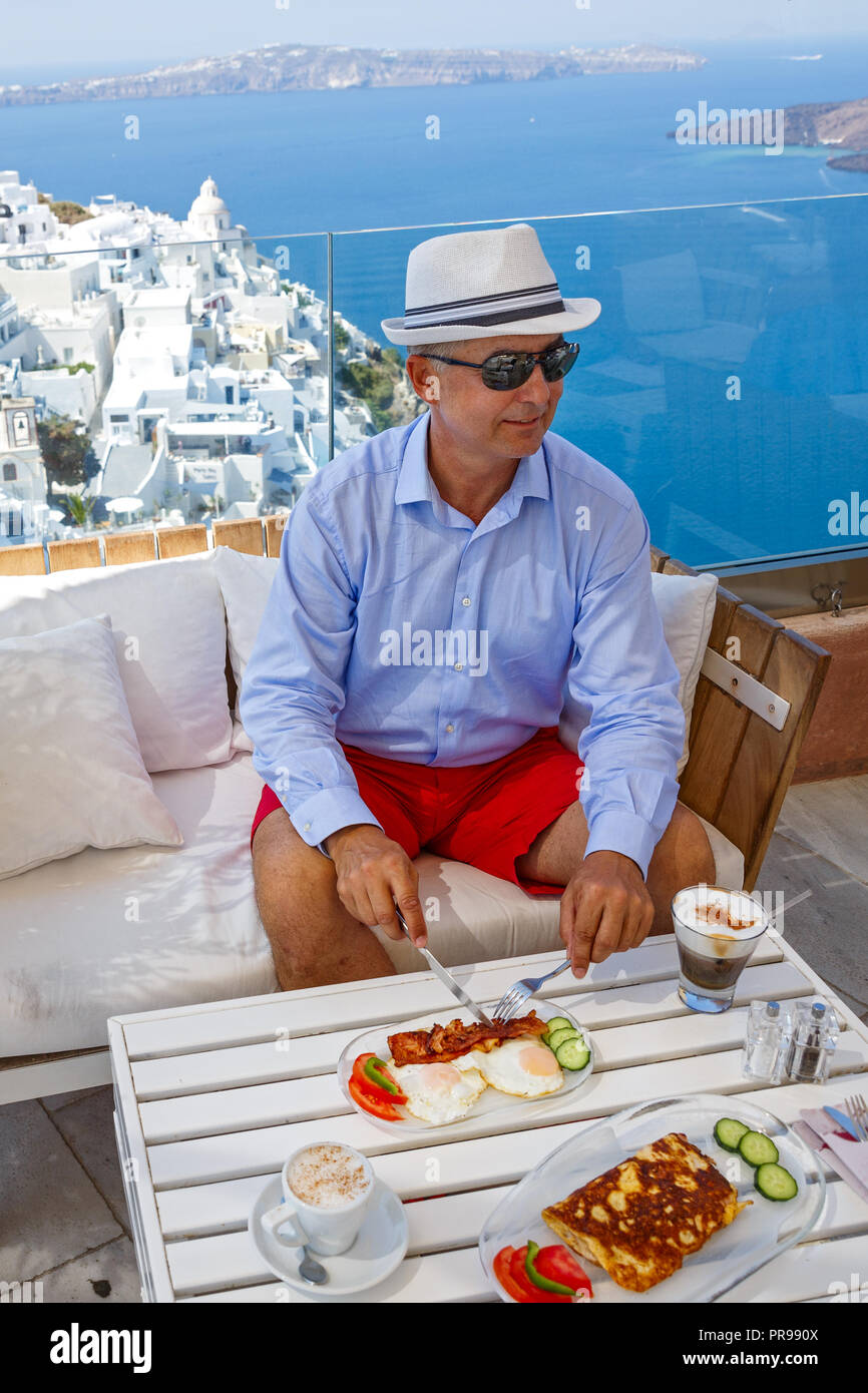 Uomo in un bar in riva al mare ha la colazione e beve caffè Foto Stock