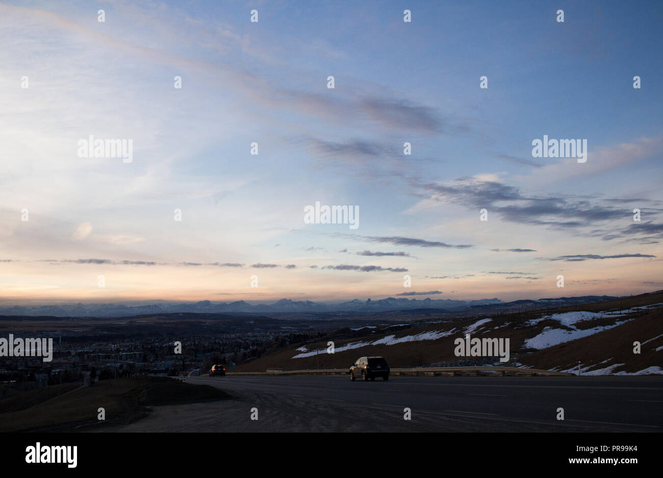 Si affaccia sulla città di Cochrane in un tramonto in inverno con fabbriche per la cottura a vapore contro le montagne rocciose. Foto Stock