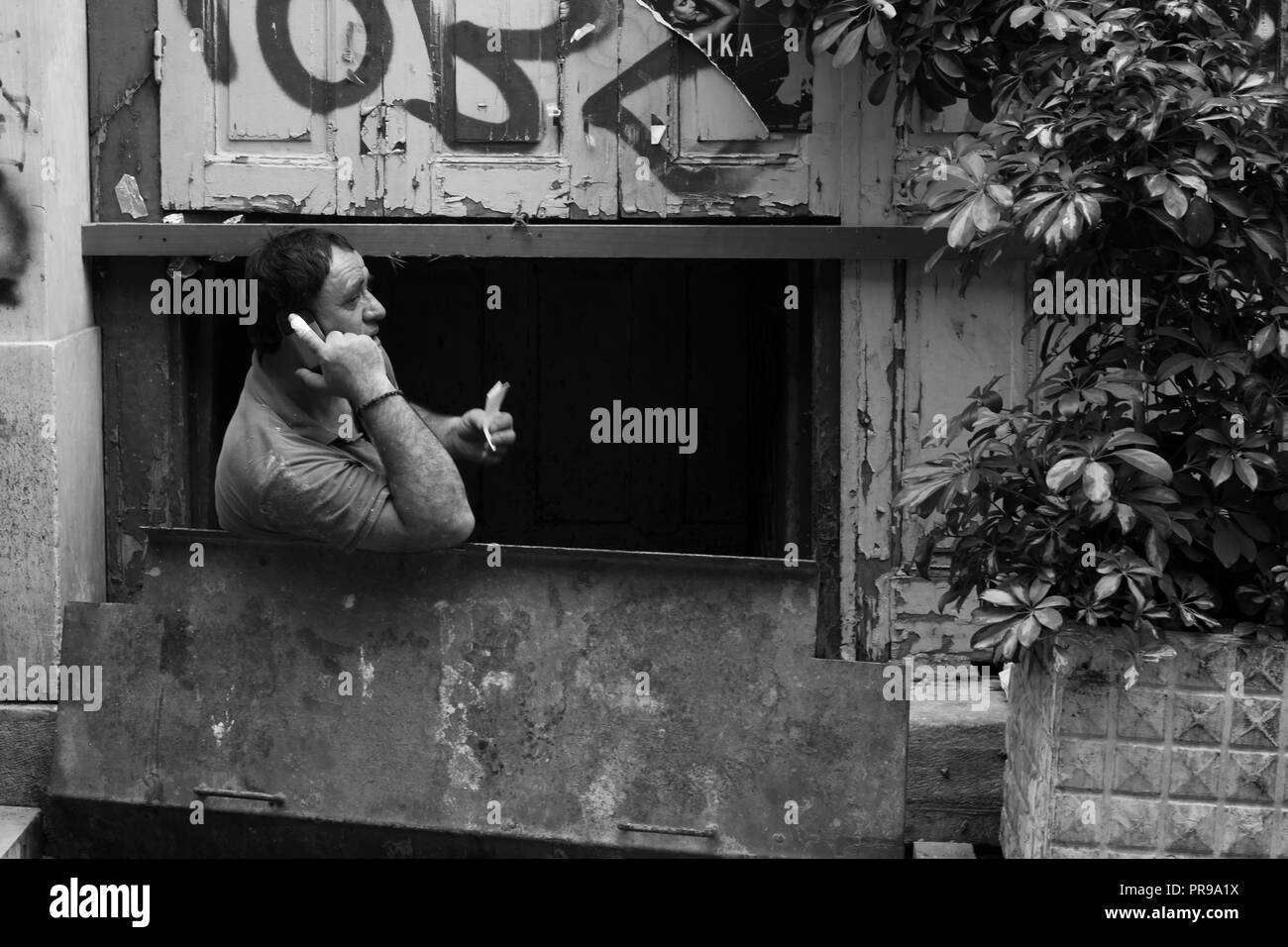 Un uomo che lavora in un seminterrato, avente una chiamata telefonica, Atene Grecia Foto Stock Un uomo che lavora in un seminterrato, avente una chiamata telefonica, Atene Grecia Foto Stock
