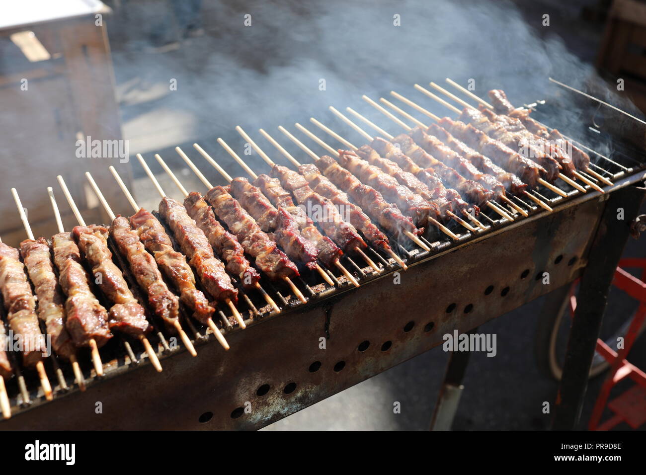 Grigliate gli spiedini di agnello sfrigolante su barbecue, tra i più popolari street food nel mondo. Foto Stock