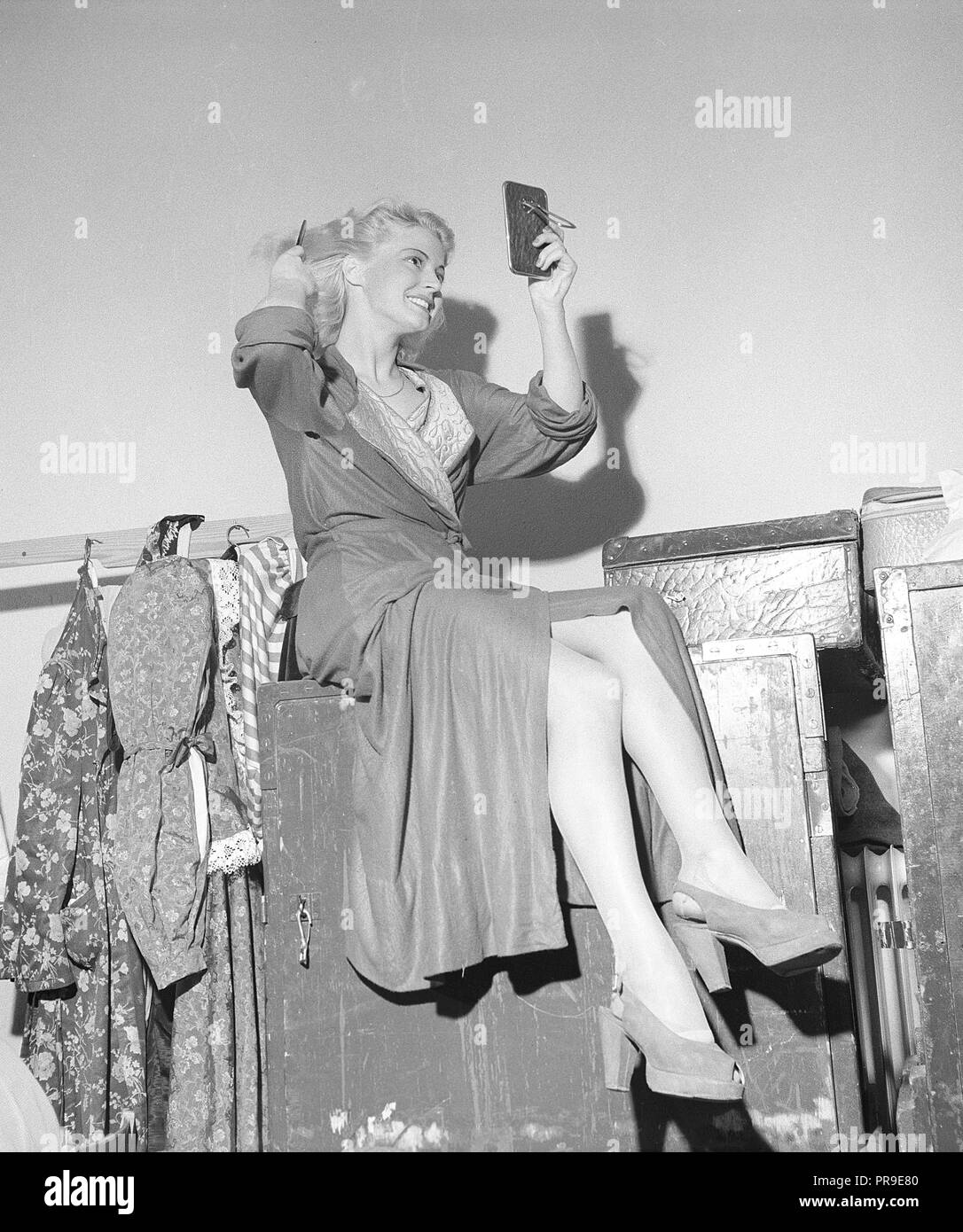 Donna che fissa i capelli negli anni '1940s. Una giovane donna bionda si guarda in uno specchio da tasca mentre pettina i capelli. Svezia 1946. Foto Kristoffersson Ref X30-1 Foto Stock