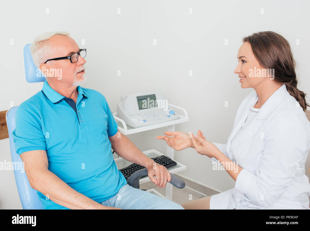 Medico di parlare con paziente senior in ufficio medici Foto Stock